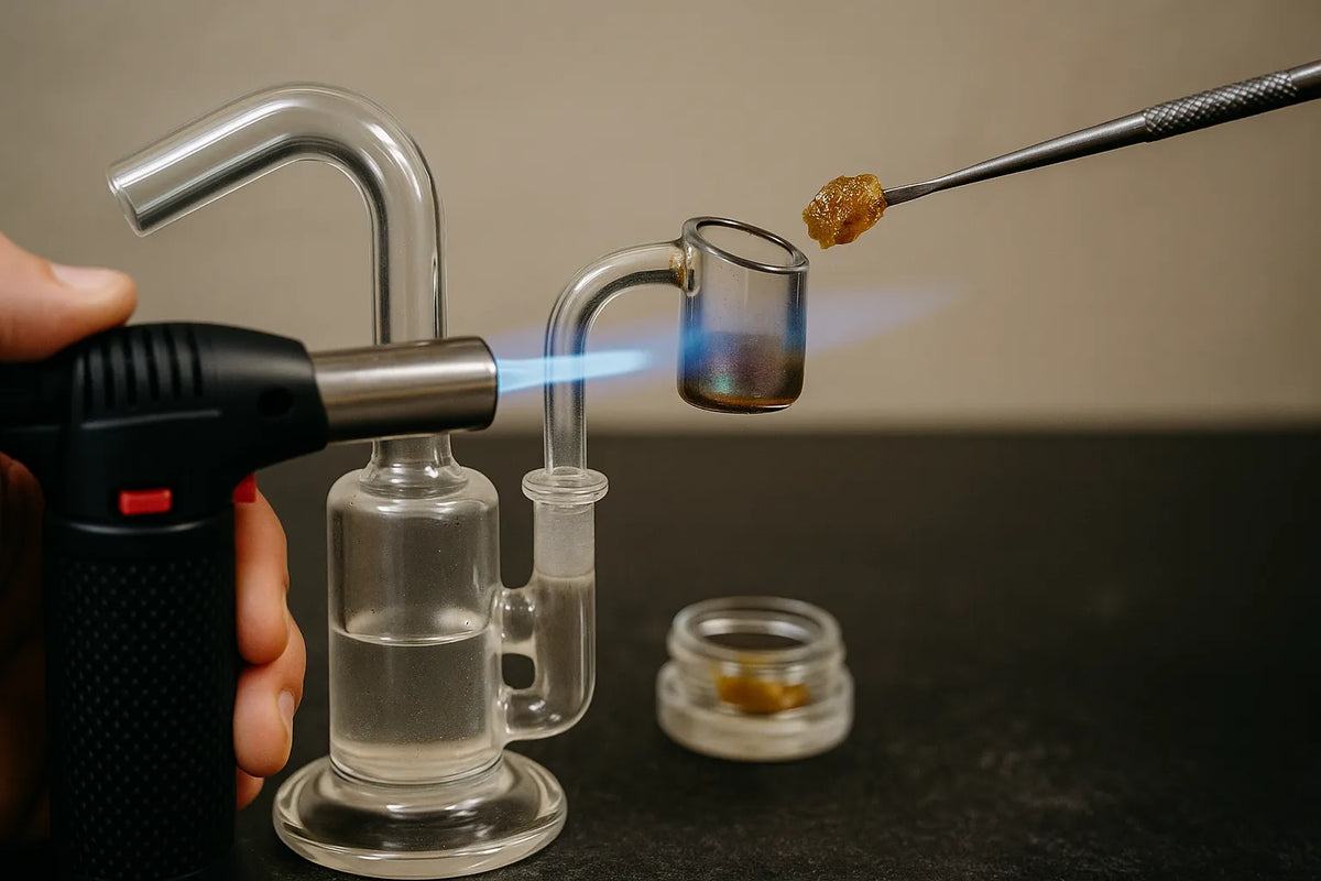 Iemand die een dab rig gebruikt om cannabisconcentraat te inhaleren, close-up in een ontspannen thuissituatie.